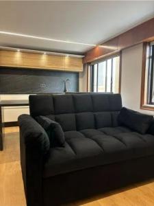 eine schwarze Couch in einem Wohnzimmer mit Klavier in der Unterkunft Dulzena Stay Apartments in A Coruña
