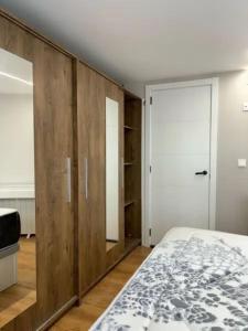 Schlafzimmer mit Holzwänden, einem Bett und einer Tür in der Unterkunft Dulzena Stay Apartments in A Coruña