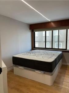 ein Bett in einem Zimmer mit einem großen Fenster in der Unterkunft Dulzena Stay Apartments in A Coruña