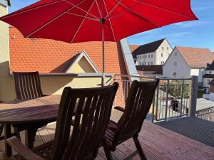 a wooden table with a red umbrella on a balcony at Gasthof Krone Fladungen in Fladungen