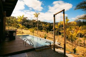 a swimming pool with a wooden deck and a swing at Herança do Vovô02 in Domingos Martins
