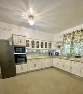 a kitchen with white cabinets and a black refrigerator at La maison blanche in Macouria