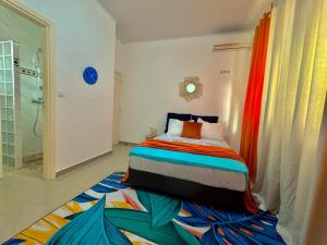 a bedroom with a bed on a colorful rug at La maison blanche in Macouria