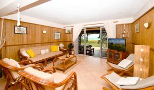 a living room with a couch and chairs and a tv at Villa Easternwind in Pointe d'Esny