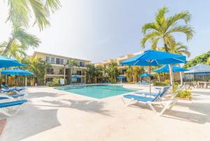 a swimming pool with blue umbrellas and chairs at Garden Condo in Sosúa