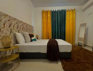 a bedroom with a large bed with colorful curtains at La maison blanche in Macouria