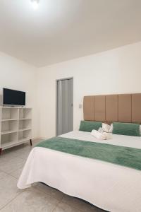 a bedroom with a large bed and a television at Karem Suítes in Canoa Quebrada