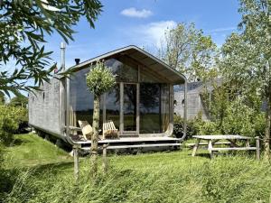 Huisje met uitzicht op de polder aan het water في Oud-Ade: منزل صغير بجدران زجاجية وطاولة