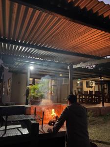 a man sitting around a fire in a patio at Gooderson Bushlands Game Lodge in Hluhluwe