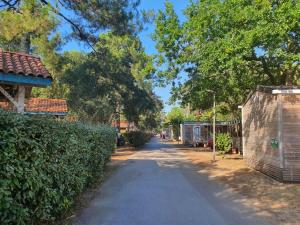 Mobile Homes by KelAir at Camping Sylvamar في لابينيه: طريق به أشجار ومبنى على جانبه