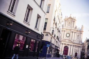 Un uomo che cammina per una strada di città con una torre dell'orologio di Hôtel de Joséphine BONAPARTE a Parigi