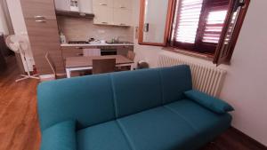 Apartamento Sole e Luna في مارتينسيكورو: أريكة زرقاء في غرفة المعيشة مع مطبخ