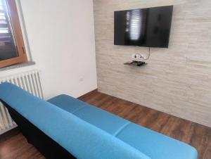 Apartamento Sole e Luna في مارتينسيكورو: غرفة معيشة مع أريكة زرقاء وتلفزيون بشاشة مسطحة