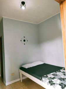 a bed in a room with a clock on the wall at La Guerta Lodging House - Uno in Pintuyan +5 photos