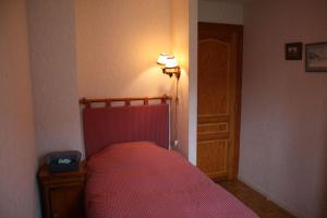 a bedroom with a bed with a red bedspread and a lamp at Chambre d'hôtes à Vecoux in Vecoux