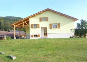 Chambre d'hôtes à Vecoux في Vecoux: منزل كبير في حقل مع ساحة