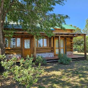 a log cabin with a porch and a tree at Sommerwind Cabañas in La Estancia