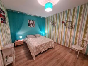 Un dormitorio con una cama y una pared azul. en Les Glycines, en Choloy