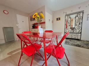 una mesa de comedor roja con sillas rojas y un jarrón de flores en Les Glycines, en Choloy 9 fotos más