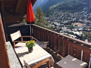 a table and chair on a balcony with a view at Chalet Memory in Zermatt