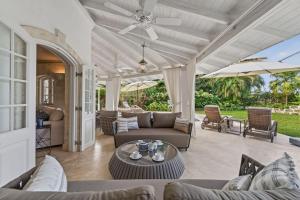 an outdoor patio with couches and tables and umbrellas at Royal Westmoreland - Villa Grove home in Saint James
