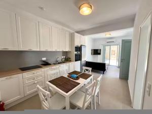 a kitchen with white cabinets and a table and chairs at Villa House Theasis in Kampos Paros +53 photos