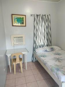 a small bedroom with a bed and a desk at La Guerta Lodging House - Uno in Pintuyan