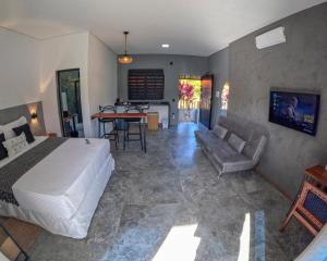 a bedroom with a bed and a couch and a table at Pousada Mon Gâté in Japaratinga