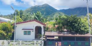 a small white house with a mountain in the background at La Guerta Lodging House - Uno in Pintuyan