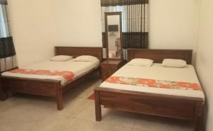 Dos camas en una habitación con espejo. en Hotel Galaxy, en Minneriya