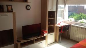 a room with a tv and a desk and a window at Apartment Your second home in Subotica