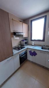 a small kitchen with white cabinets and a window at Appartement Ksour in Sraghna