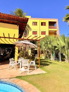 Una piscina con sillas y una sombrilla al lado de un edificio. en Pousada Sunrise Beach Cumbuco, en Cumbuco
