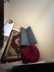 a living room with a red chair and a rug at Small apartment 10 minutes from Abu Dhabi Airport for Married Couple or Single with parking in Abu Dhabi
