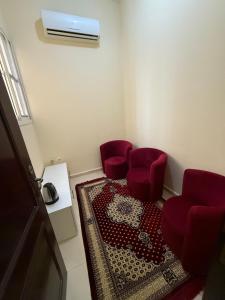 a room with two red chairs and a rug at Small apartment 10 minutes from Abu Dhabi Airport for Married Couple or Single with parking in Abu Dhabi