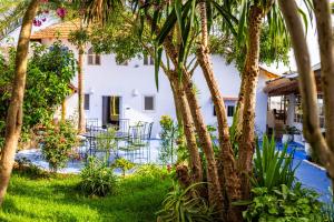 a courtyard with palm trees and a white building at Maison d'hotes Berbari in Asilah