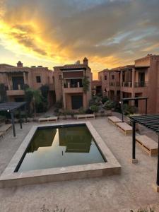 a courtyard with a pool in front of some buildings at Appartement Ksour in Sraghna