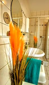 a bathroom with a sink and a vase with orange flowers at Kahler Pőn in Willingen +22 photos