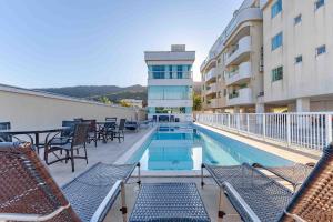 a hotel balcony with chairs and a swimming pool at Apto Aconchegante na Praia de Bombas com Piscina in Bombas