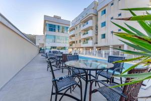 a balcony with tables and chairs and a pool at Apto Aconchegante na Praia de Bombas com Piscina in Bombas