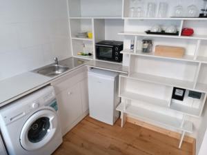 a white kitchen with a washing machine and a sink at Studio Berlin Center in Berlin