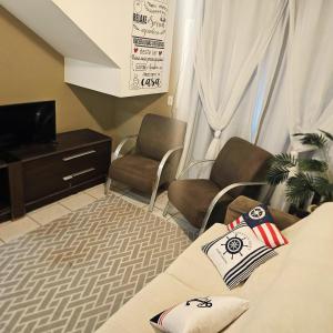 a room with a bed and two chairs and a tv at Villa Enseada - Charme e conforto a 650m da Praia da Enseada in Guarujá