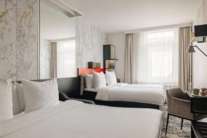 a hotel room with two beds and a desk at Leonardo Boutique Hotel The Lancaster Amsterdam in Amsterdam