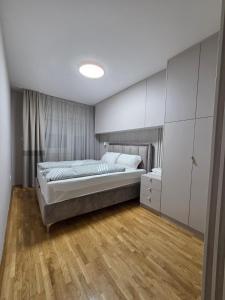 PARADISO STAN Bijeljina في بيه لينا: غرفة نوم مع سرير وأرضية خشبية