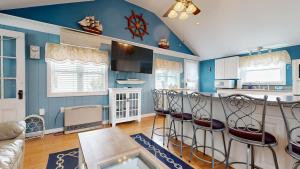 a kitchen with blue walls and a bar with stools at Sand Life #2 by Bayley Vacation Rentals in Old Orchard Beach