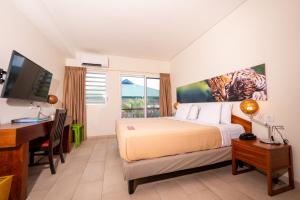 a bedroom with a bed and a desk and a computer at Eco Torarica in Paramaribo