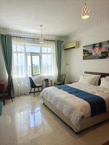 a bedroom with a large bed and a table and chairs at Zawadi Apartment in Dar es Salaam