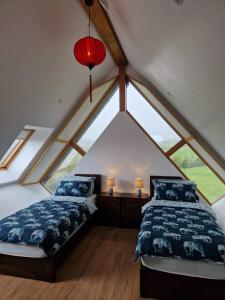 Un dormitorio abuhardillado con dos camas y una lámpara roja. en Black Lodge - Sea view with deck garden, en Garrylucas
