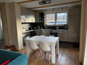 una cucina con tavolo e sedie bianchi di Behagliches Cottage am See a Fürstenberg/Havel