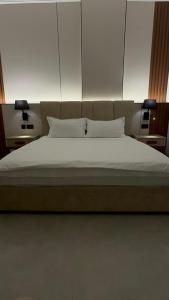 Una cama con sábanas blancas y almohadas en una habitación. en Inter Town Hotel, en Salalah